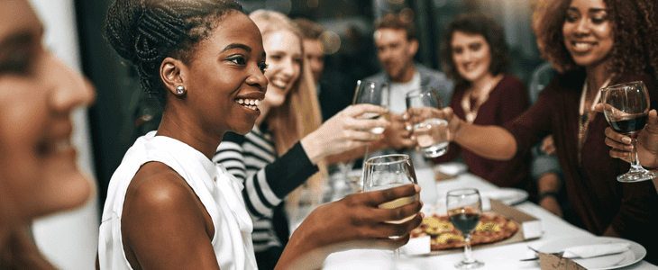 A group of friends celebrate and cheers at dinner